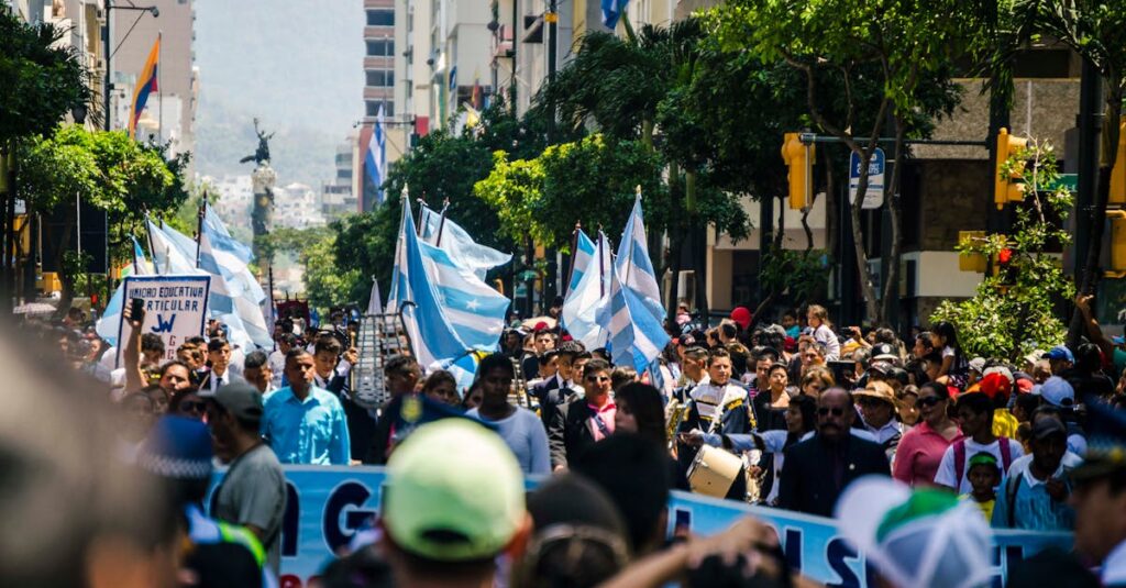 A lively urban protest with people holding flags and signs on a sunny day.