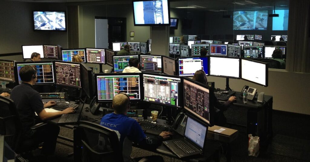 A bustling control room with people working on multiple computer monitors.